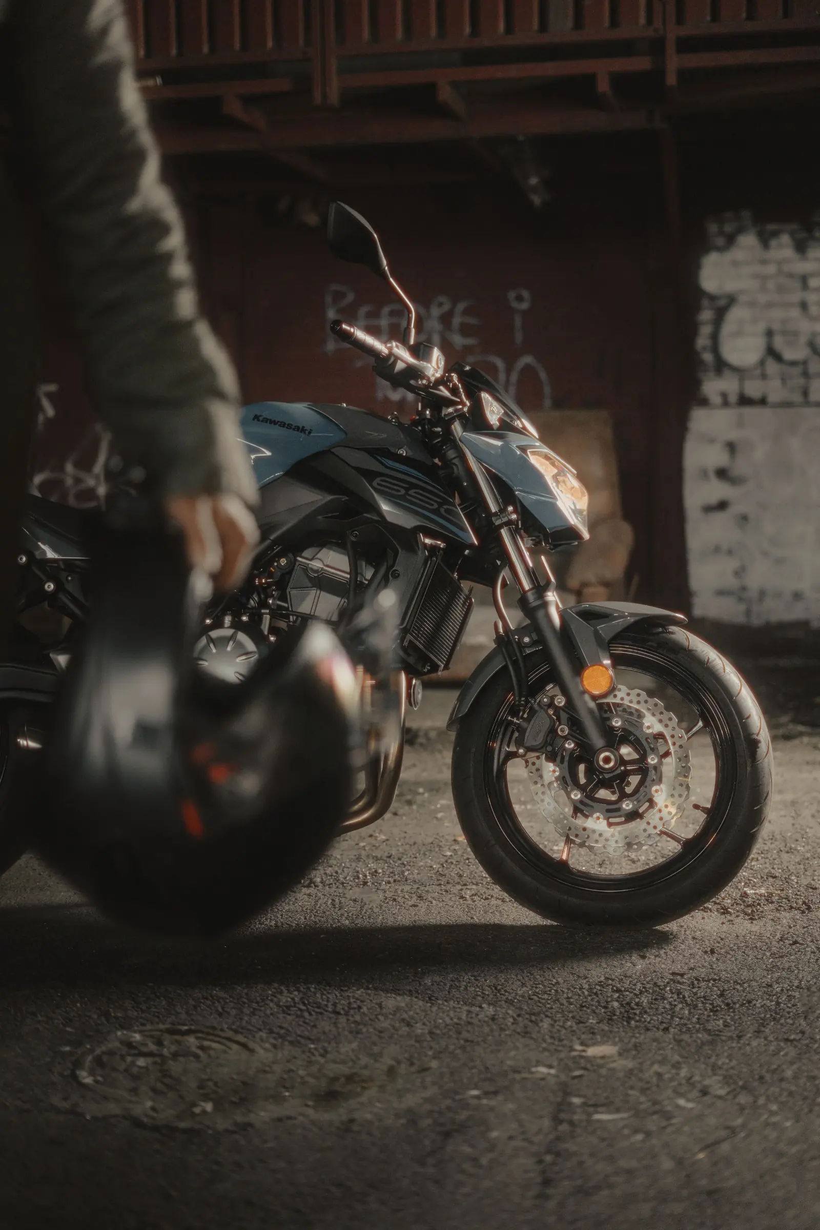 Hand hält einen Motorradhelm, dahinter ein Motorrad