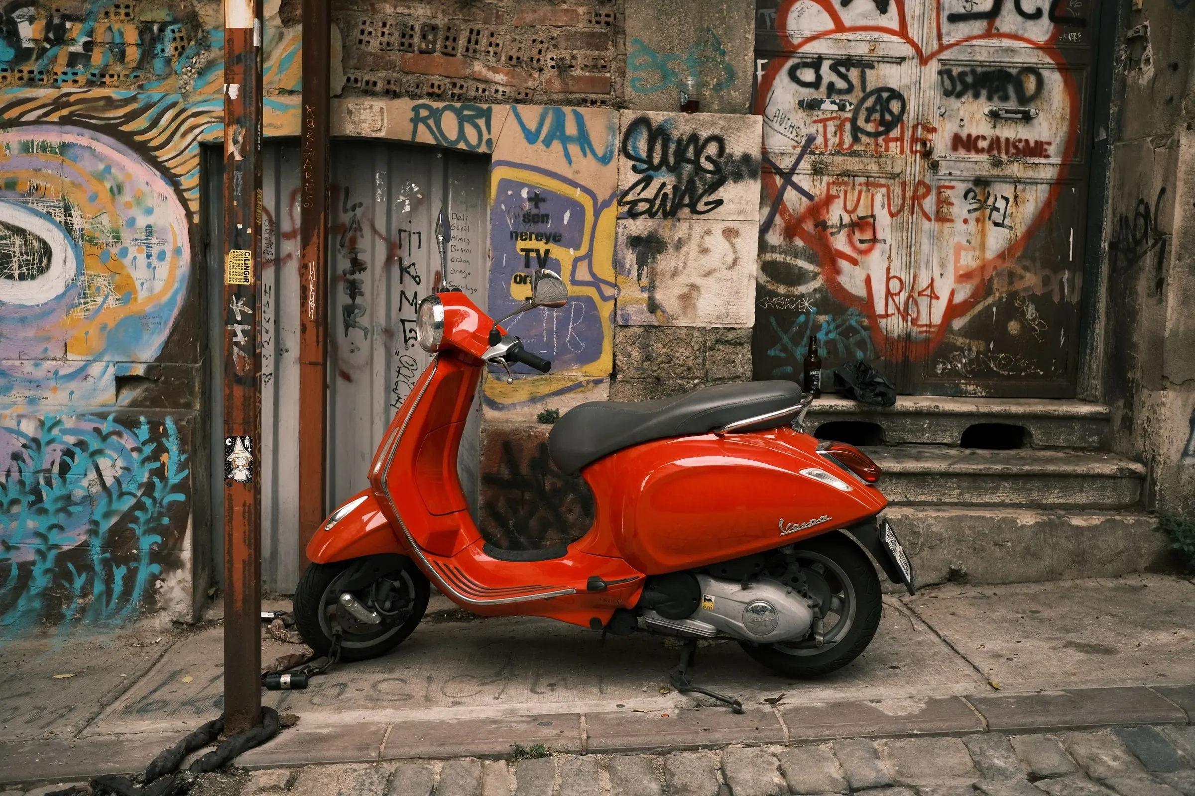 Roter Motorroller vor einer bemalten Hauswand